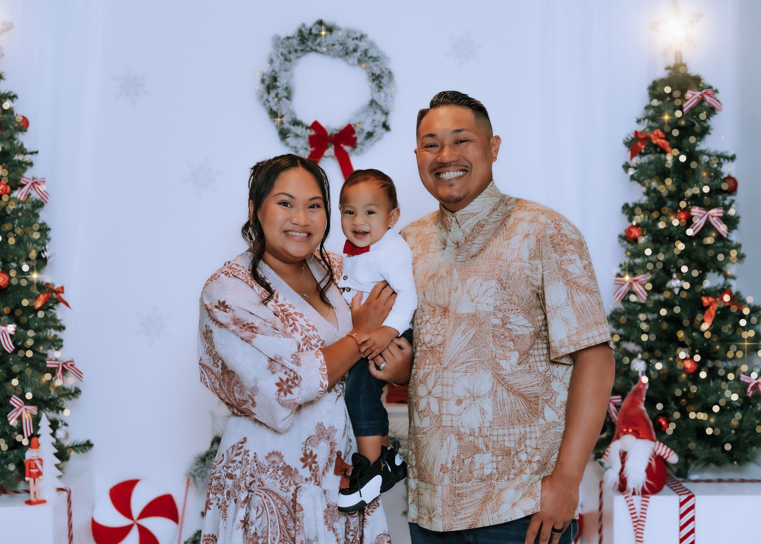 Family poses for Christmas photos in coordinated outfits with decorated tree and peppermint props.