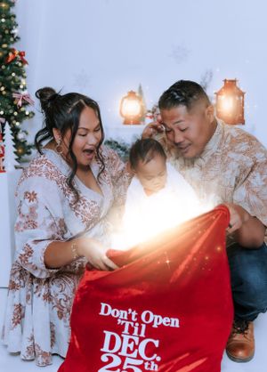 Family opens a red 'Don't Open Until Dec 25' bag during Christmas photo session.
