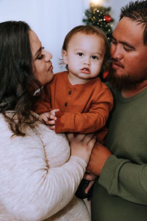 A family shares tender kisses in a series of intimate holiday portraits against a white background.