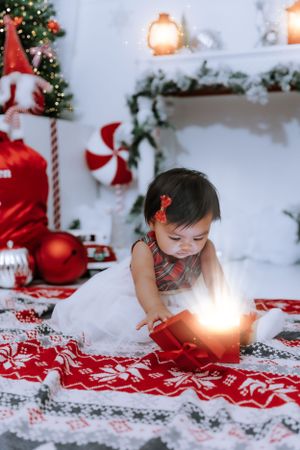 Child explores holiday setup with glowing lights and red Christmas decorations.