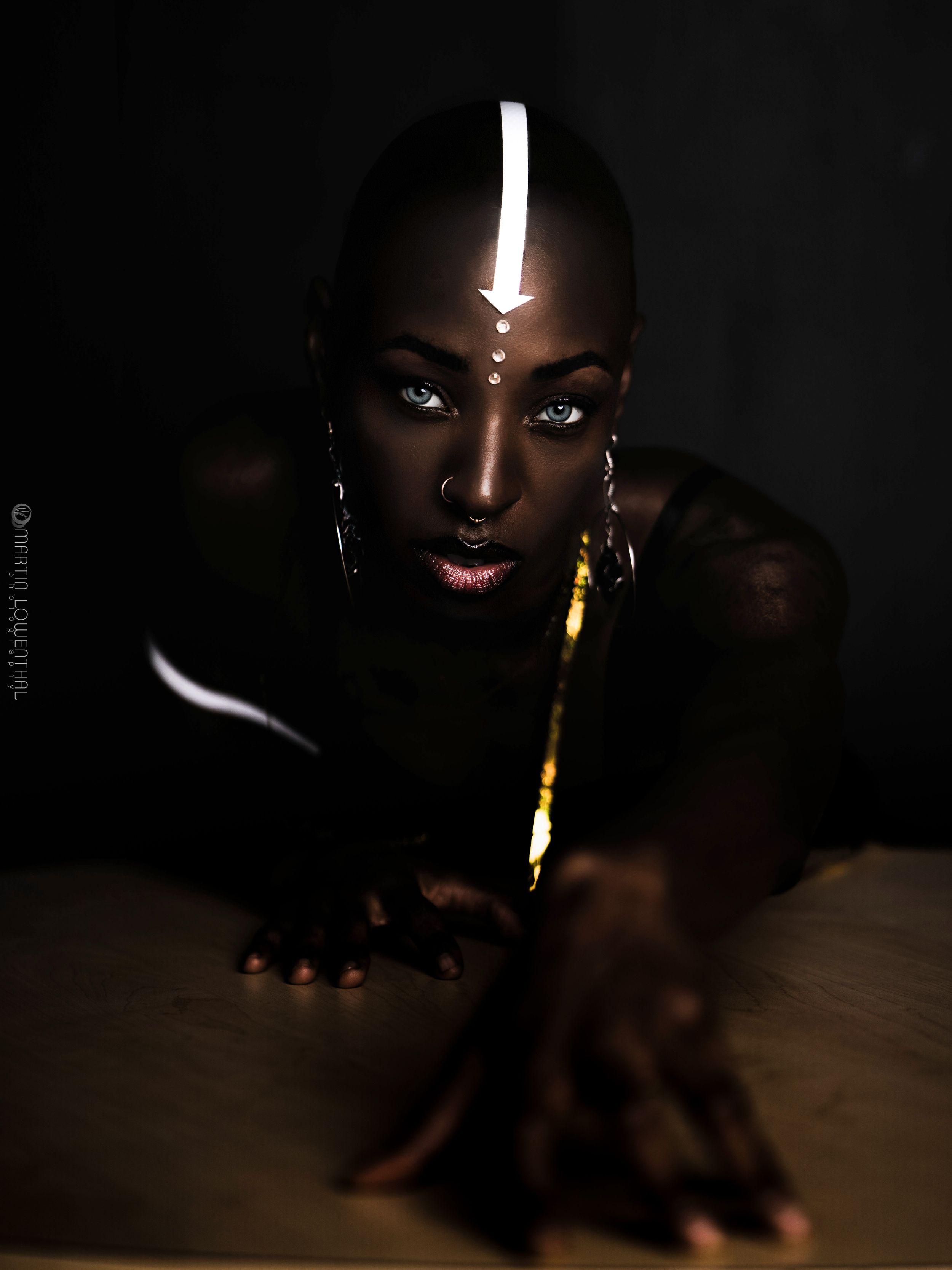 Dramatic low-key portrait series showing a glowing candle in dark lighting against dark skin.