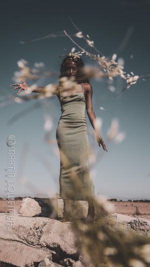 Artistic portrait in beige dress with motion blur effect in desert setting.