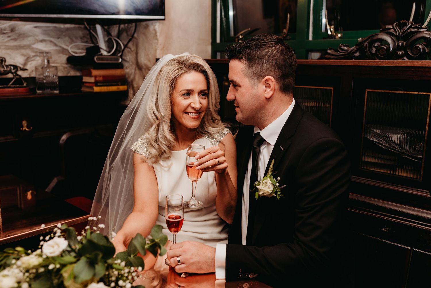 A couple enjoying their first drink together, looking at each other with big smiles on their faces.