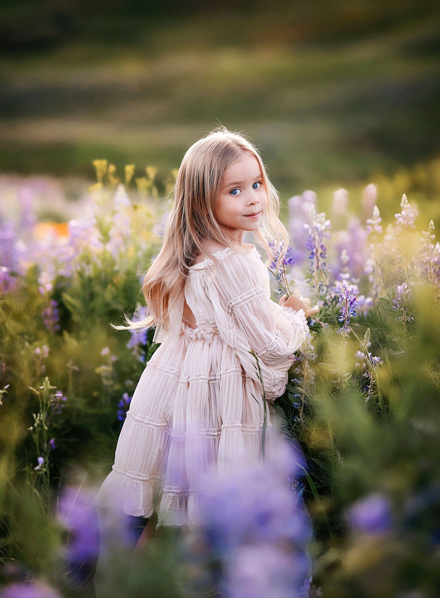 A cute little girl turns around and gives a sweet smile in the flower fields of Crested Butte.