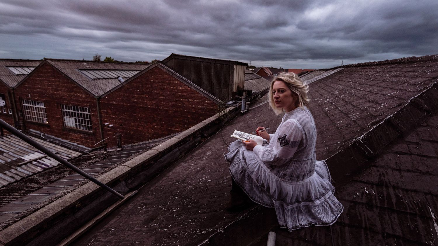 Dramatic rooftop view with stormy clouds over brick buildings.
