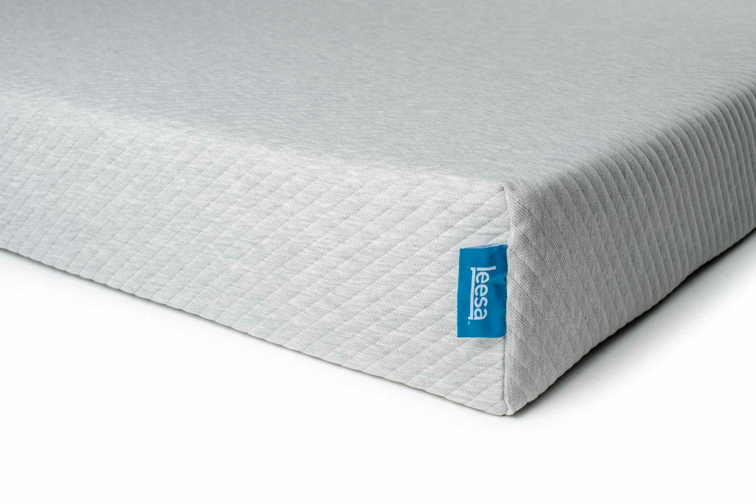 Close-up of a gray textured mattress corner with blue brand label.