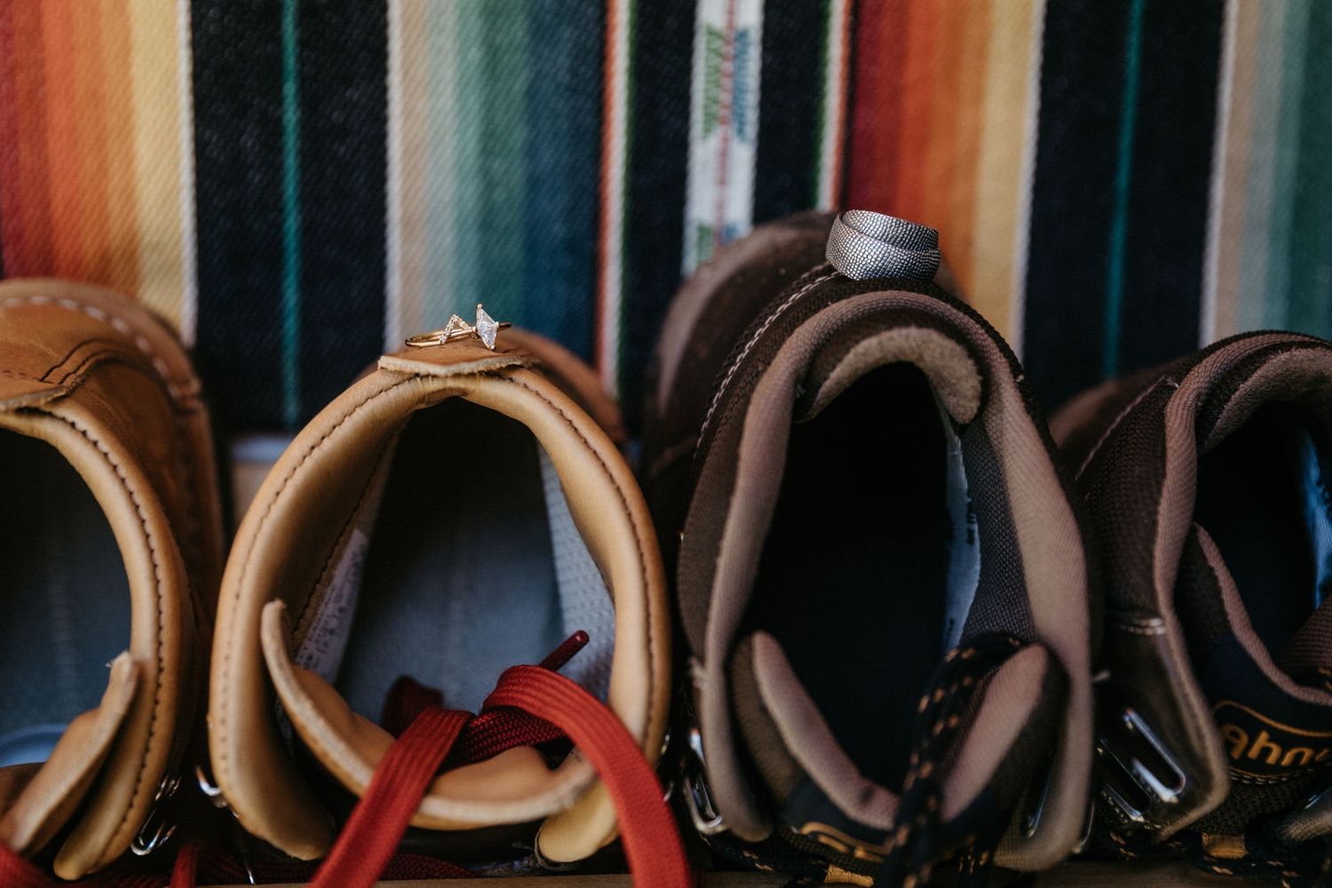 A collection of brown leather boots lined up against a colorful striped background.