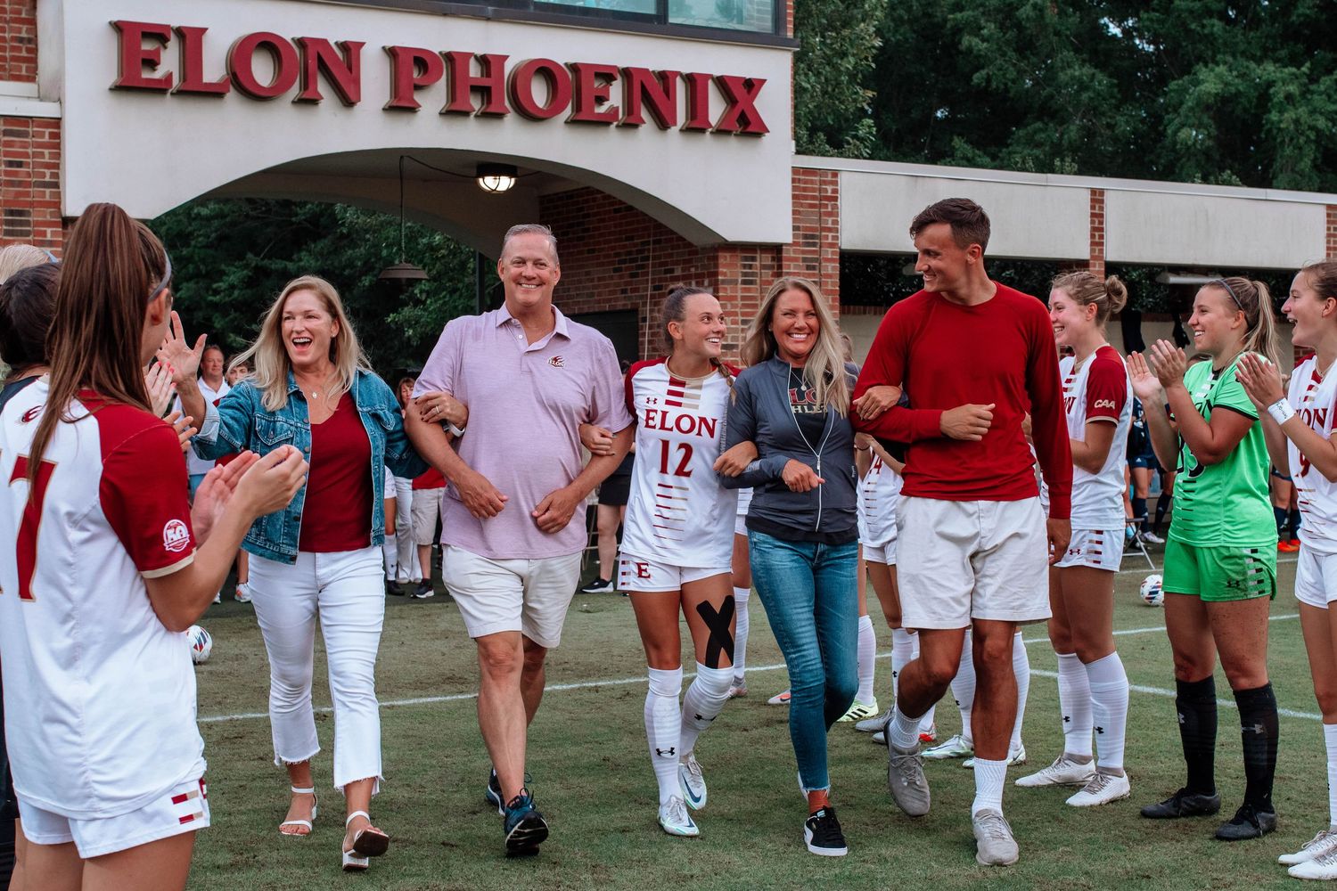 Cheerful group gathers outside the Elon Phoenix stadium entrance during a sporting event.