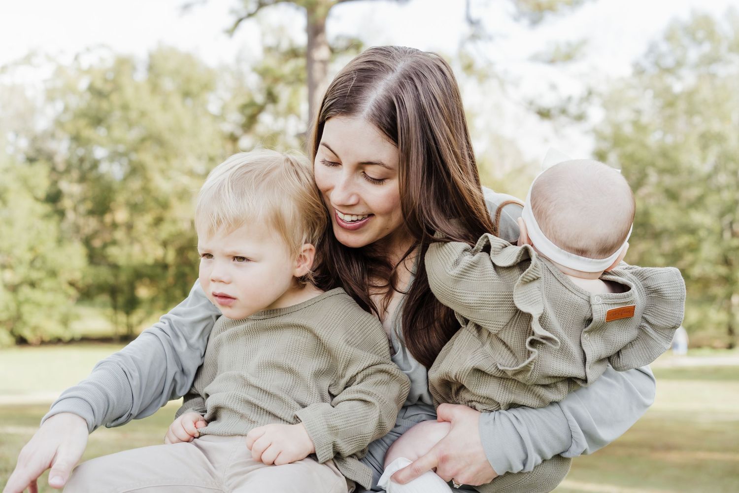 A mom holds her two children in her lap while relaxing at Highland Park in Baton Rouge.
