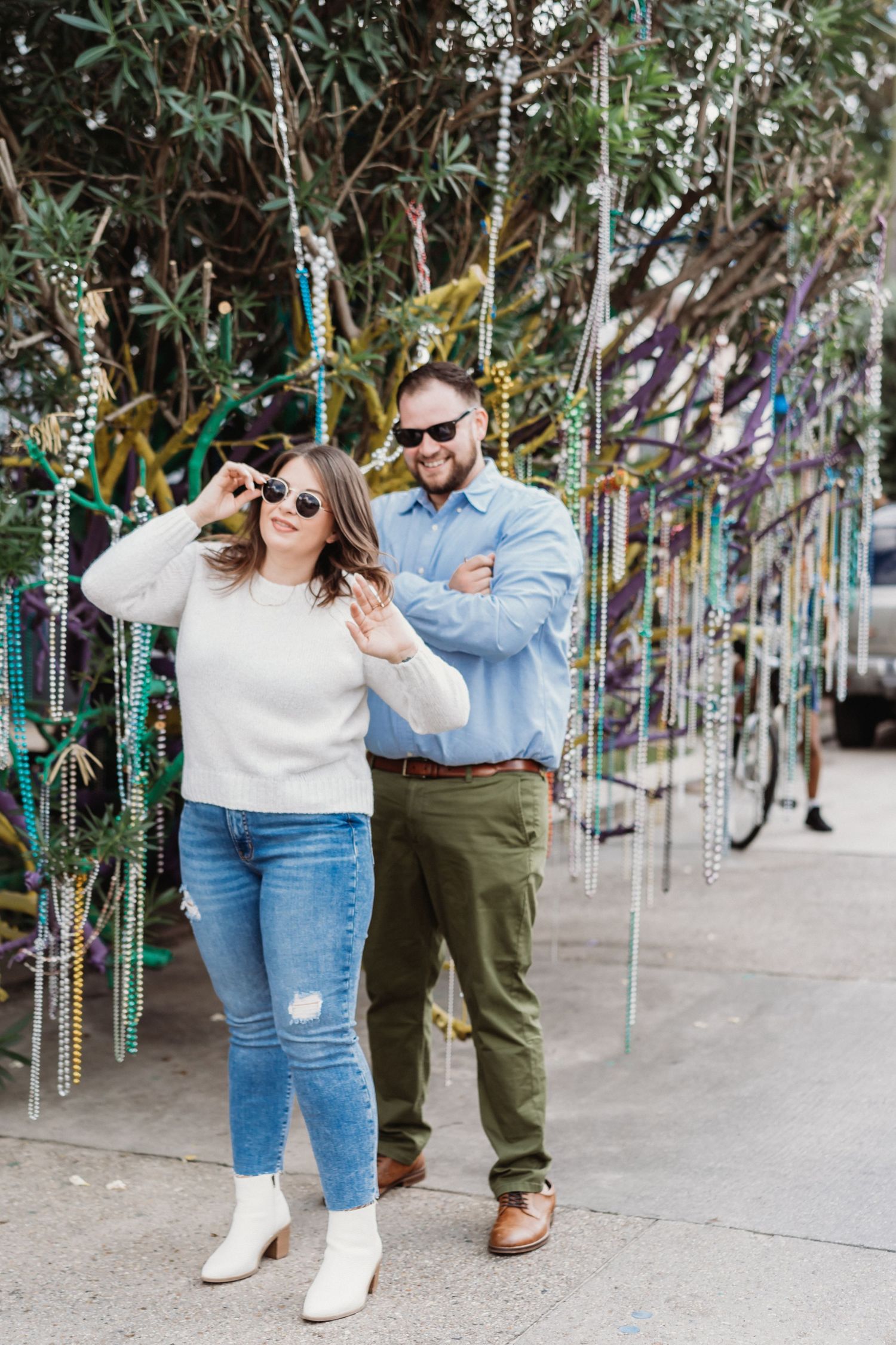A couple jokingly poses in front of a Mardi Gras tree.