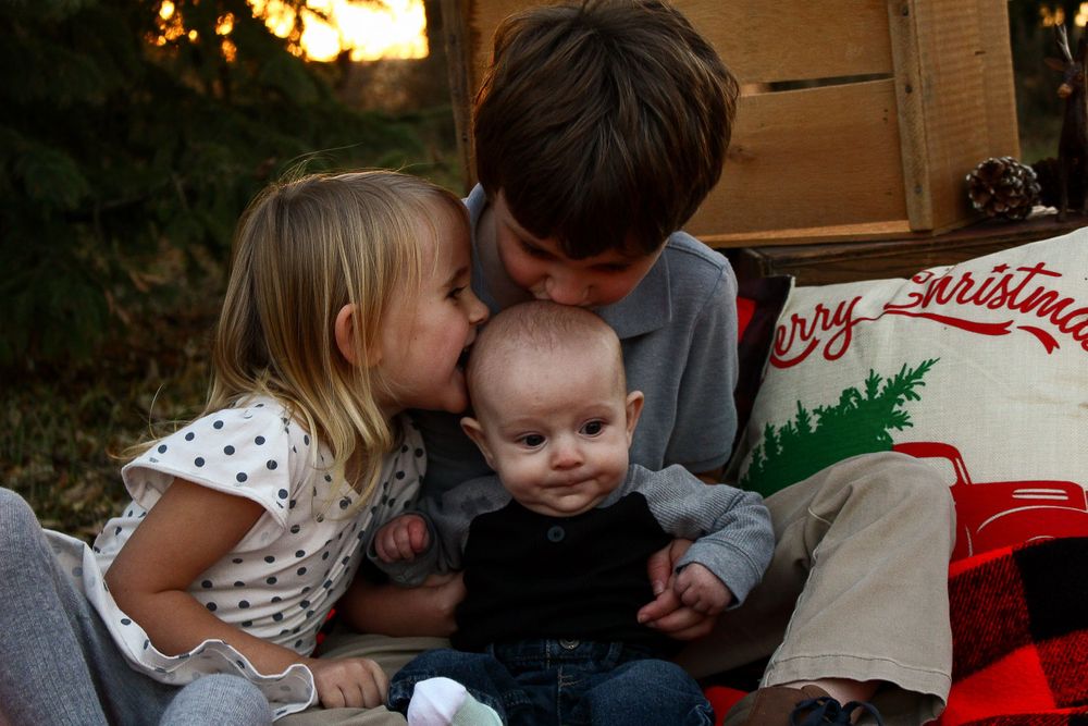 Cozy indoor family moment with holiday decorations visible in the background.