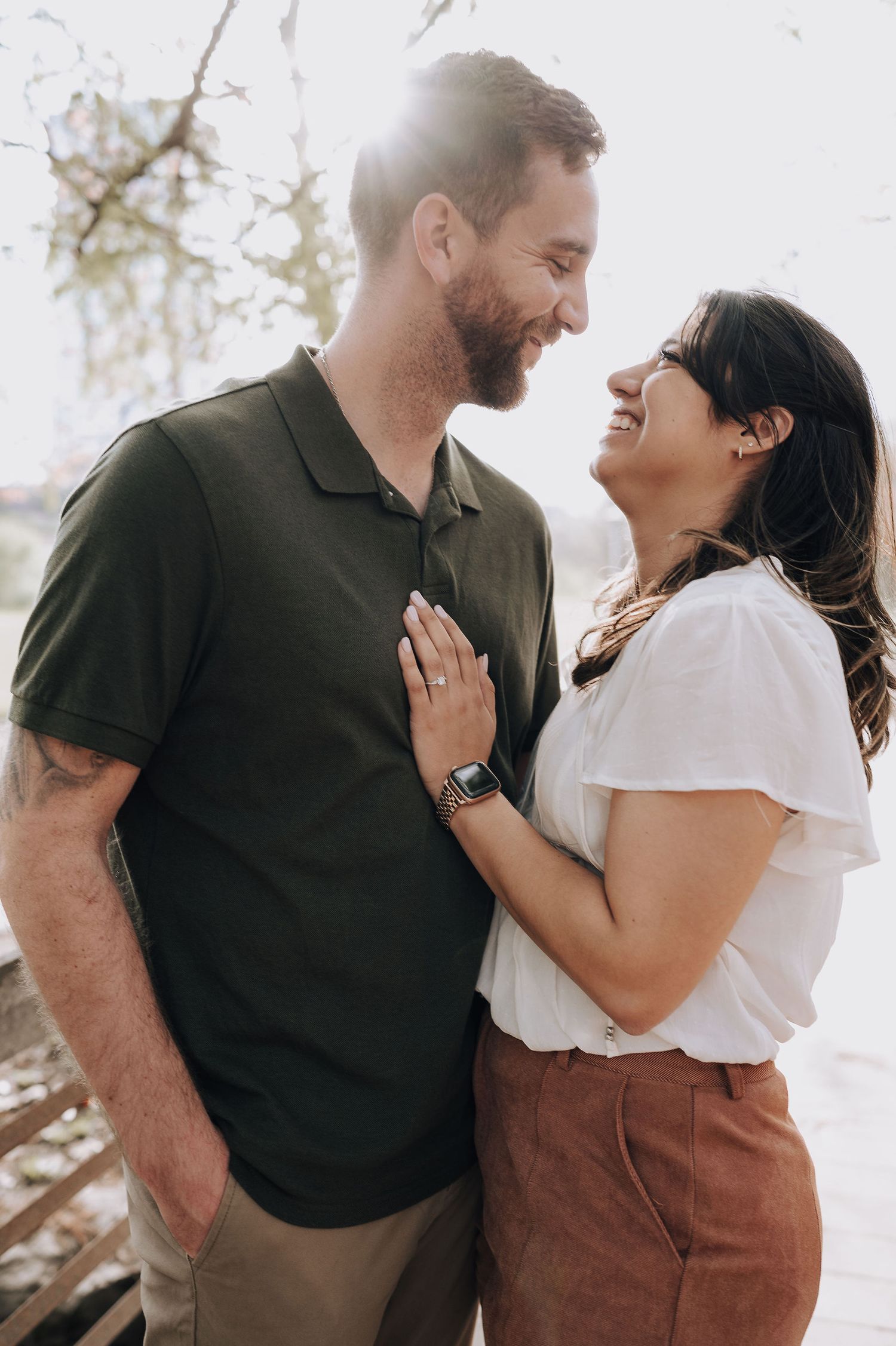 A joyful couple shares a candid moment together in natural sunlight.