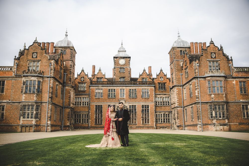 Wedding couple poses in front of a majestic Victorian Gothic mansion on a cloudy day.
