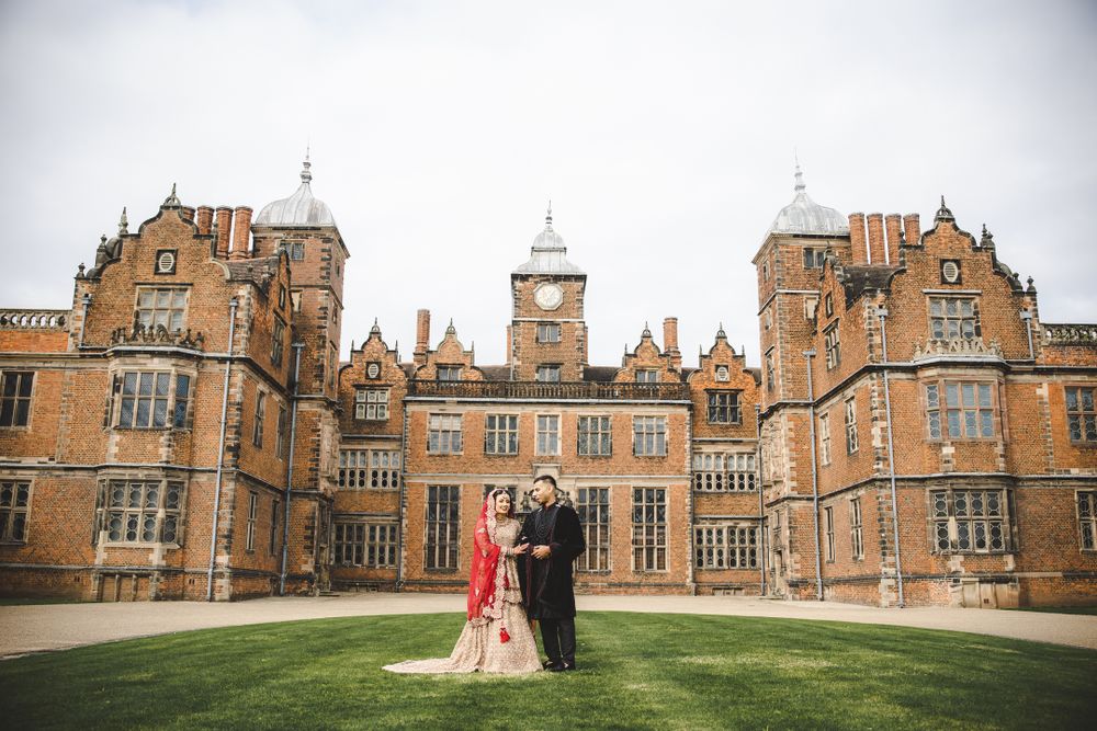 Romantic wedding portrait with couple standing before stunning historic British manor house.