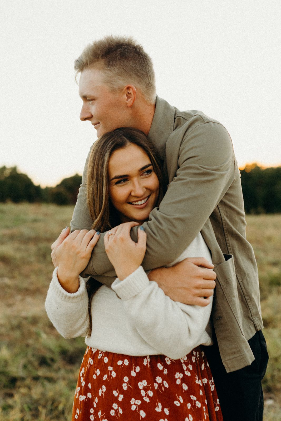 A romantic sunset photoshoot in a field with warm golden light and intimate poses.