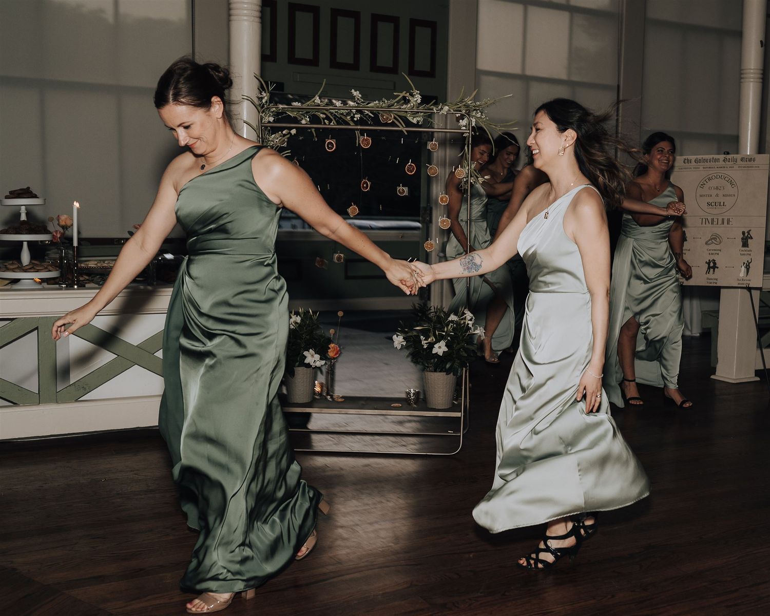 Two women in elegant dresses dancing together at a wedding celebration.