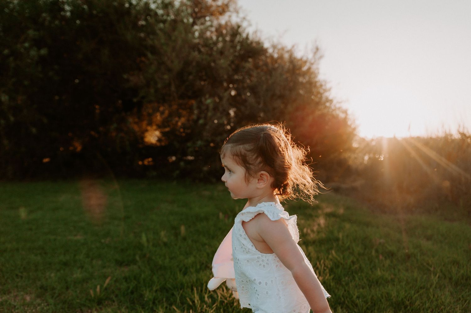 A small child wearing a white outfit running through a grassy field at sunset.
Altona Family Photographer Melbourne