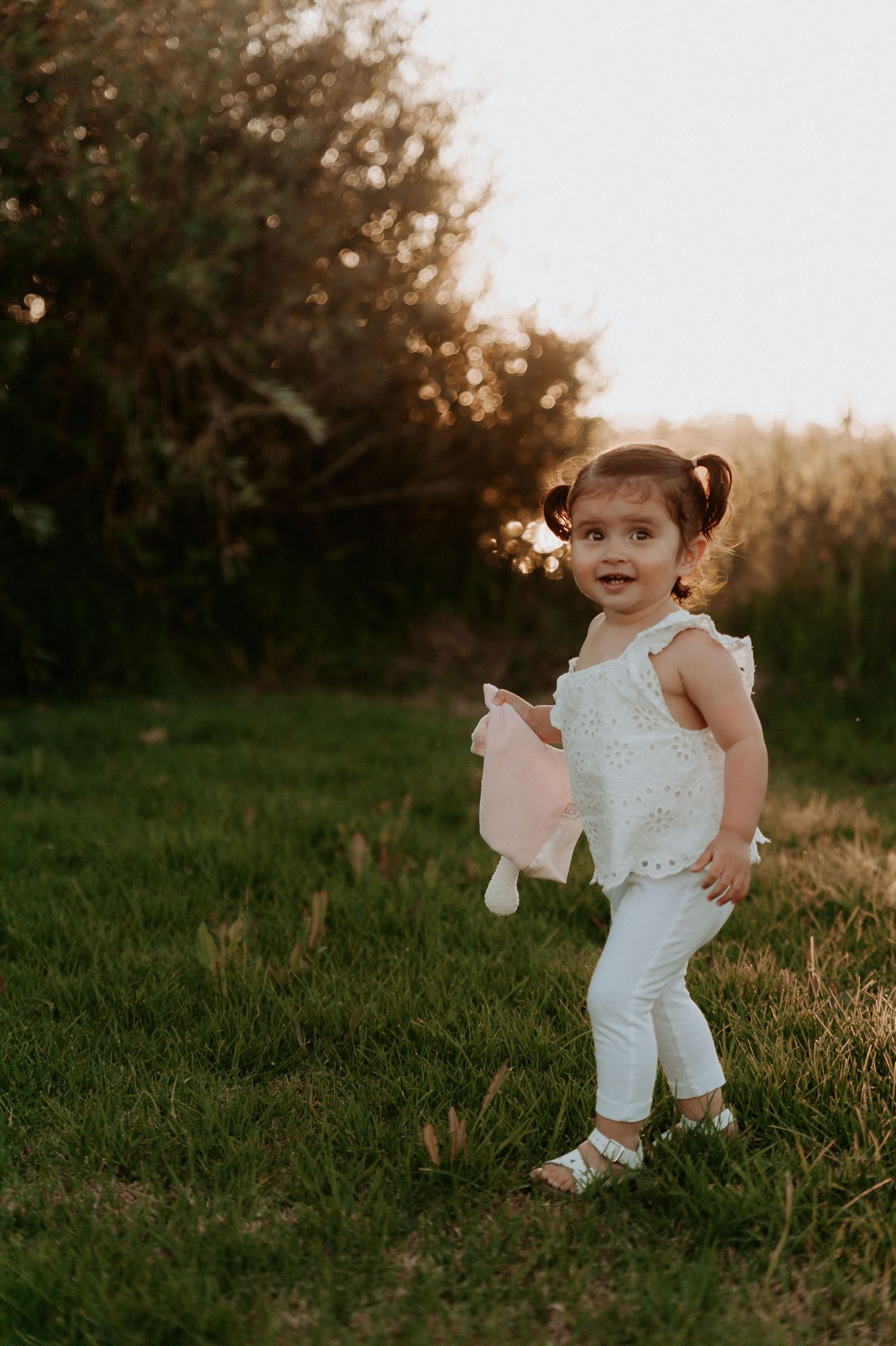 A toddler in white clothing playing in a grassy field during golden hour.
Altona Family Photographer Melbourne
