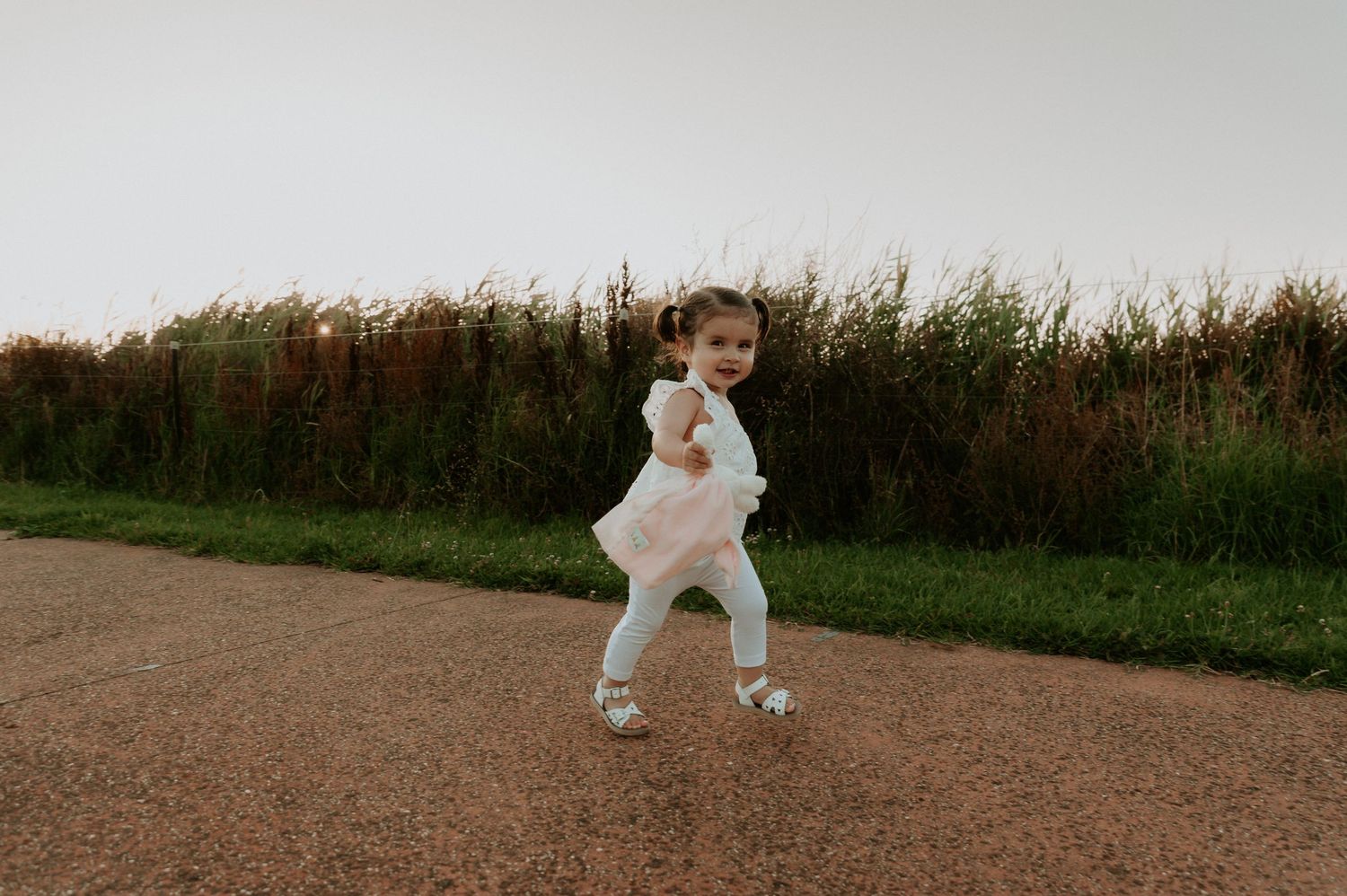 A small child skips down a dirt path surrounded by tall grass.
Altona Family Photographer Melbourne