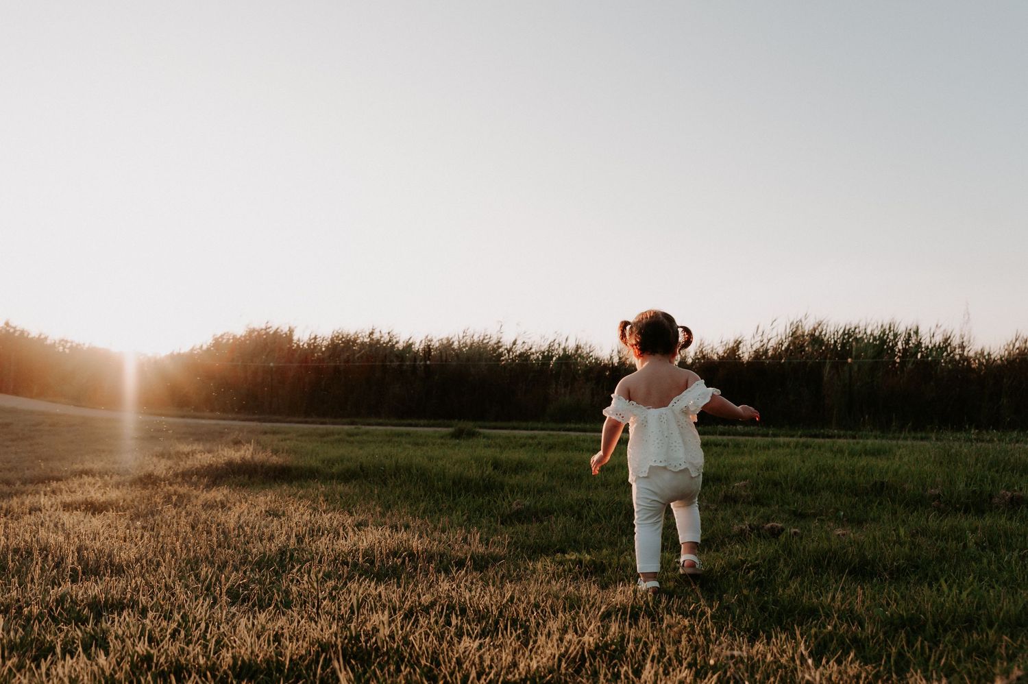 A silhouetted figure stands in a grass field during golden hour with arms outstretched.
Altona Family Photographer Melbourne