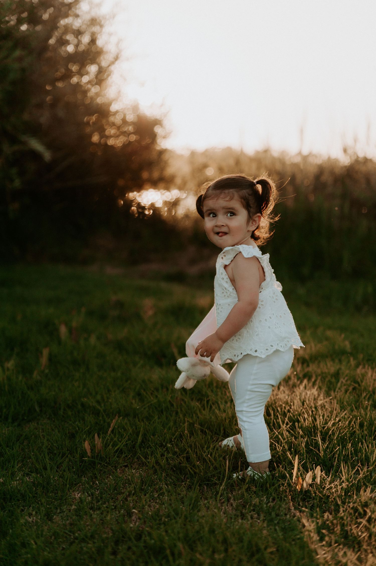 A child in white clothing playing in a sunlit field during golden hour.
Altona Family Photographer Melbourne