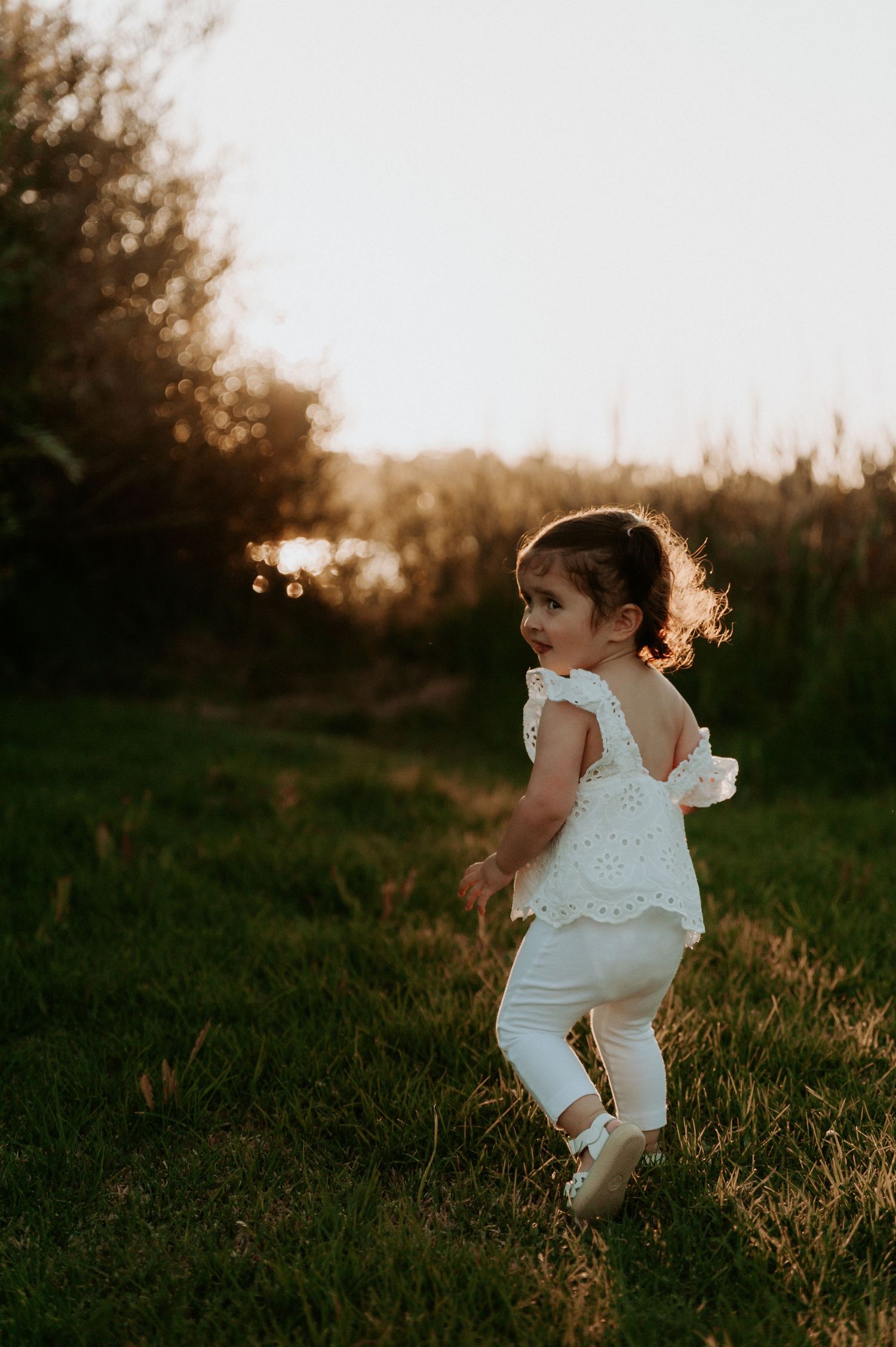 A little one running through a meadow in white clothing at sunset.
Altona Family Photographer Melbourne