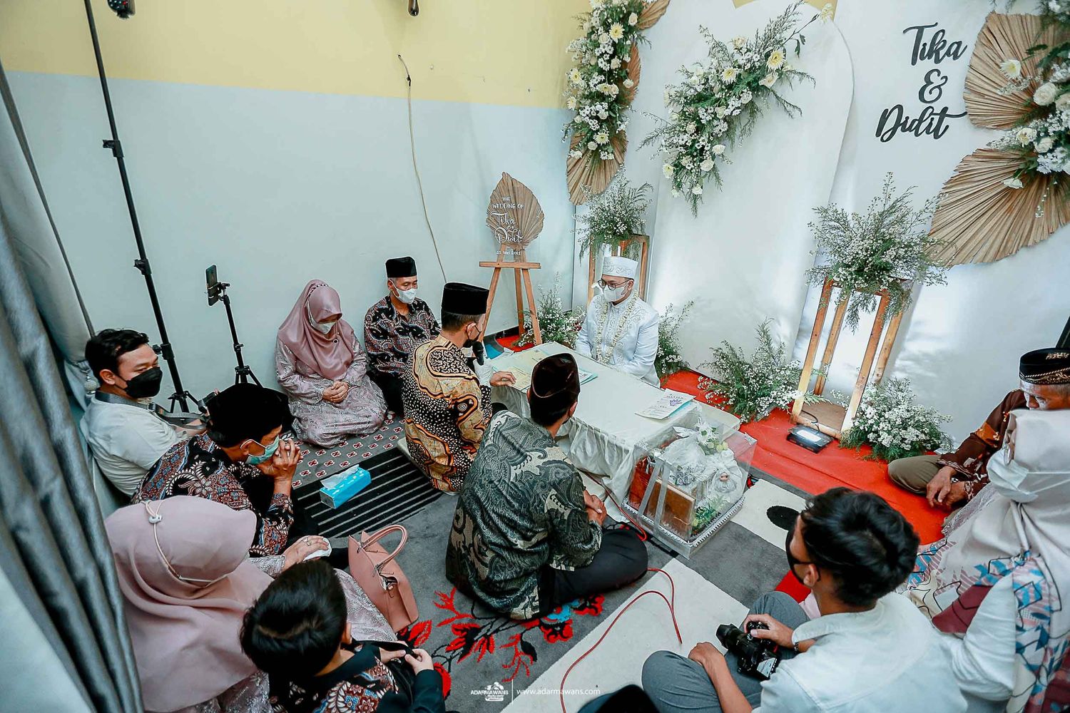 Intimate indoor gathering with guests seated on floor during traditional ceremony.
