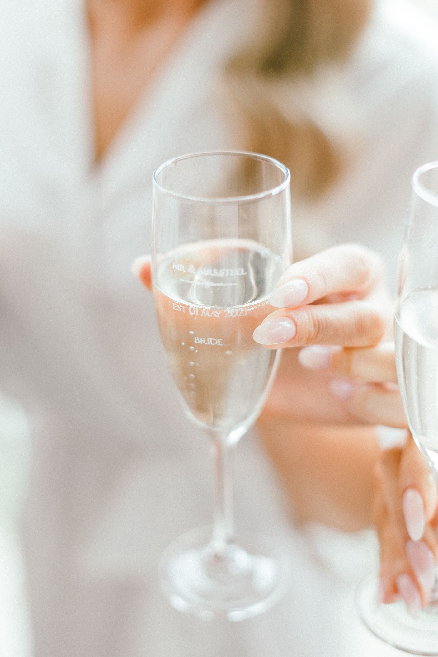Hand holding champagne flute with bubbles rising in soft light.