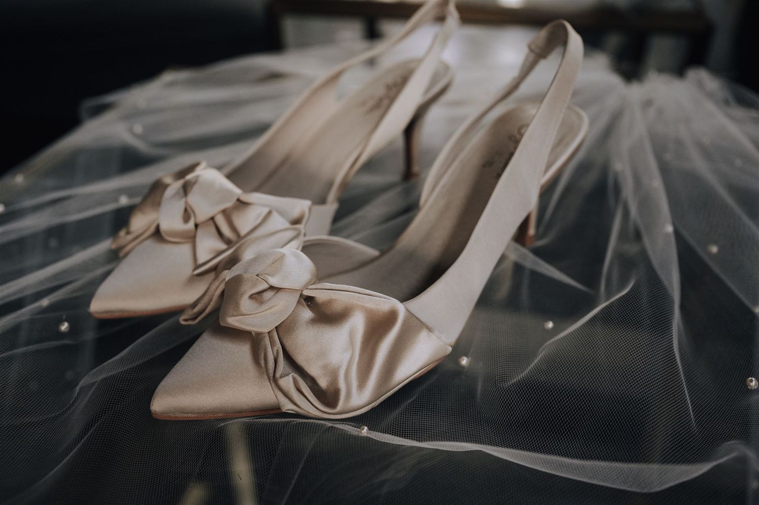 Elegant cream-colored bridal shoes with bow details on tulle fabric.