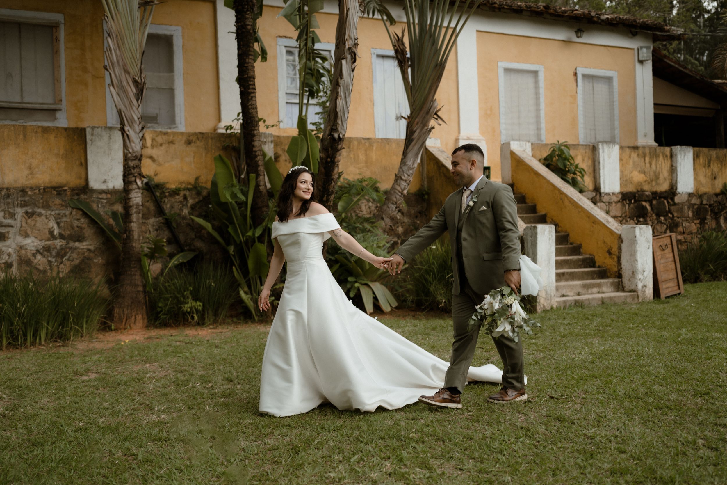 Wedding couple shares intimate moments on a grassy lawn near a historic building.