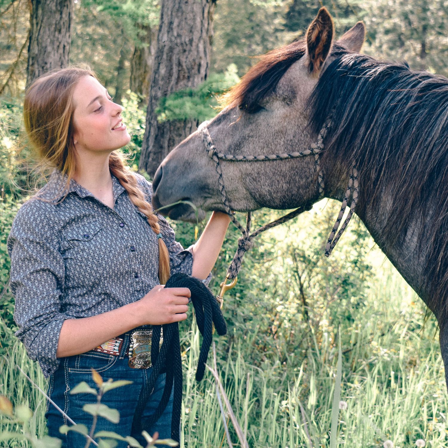 A special moment between horse and rider in a forest setting.