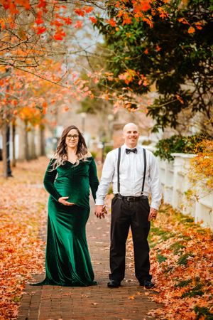 Romantic fall engagement photos with couple walking through orange autumn leaves.