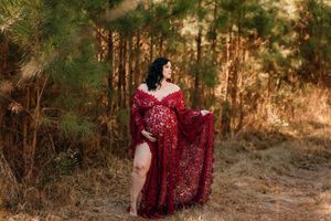 Maternity portrait session in burgundy dress against golden sunset forest backdrop.