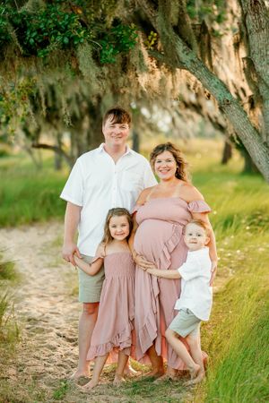 Family in coordinating pink and white outfits posing outdoors in natural setting.