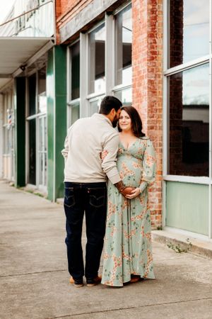 A couple shares intimate moments during their maternity session along a vintage storefront.