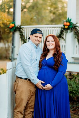 A couple poses together outdoors wearing coordinating blue and khaki outfits in a romantic photoshoot.