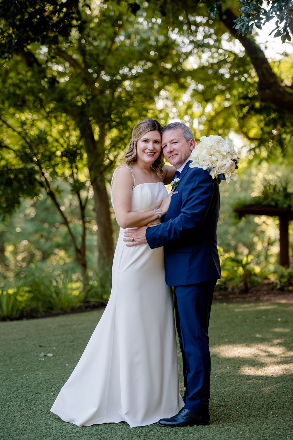 A tender wedding portrait captured in a lush garden setting.