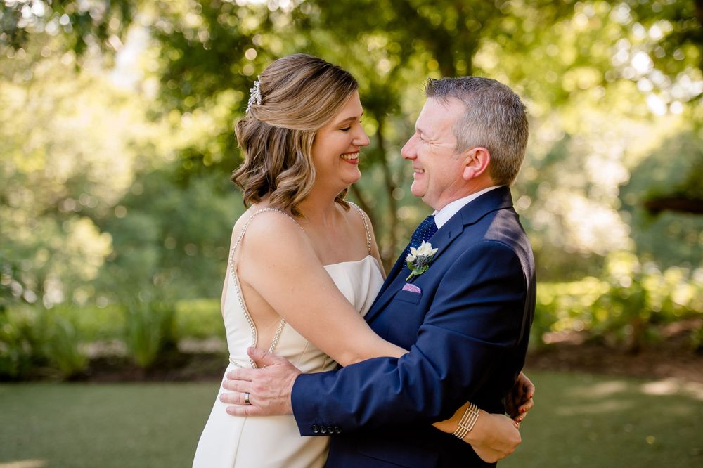 A joyful wedding portrait taken in a sun-dappled garden setting.