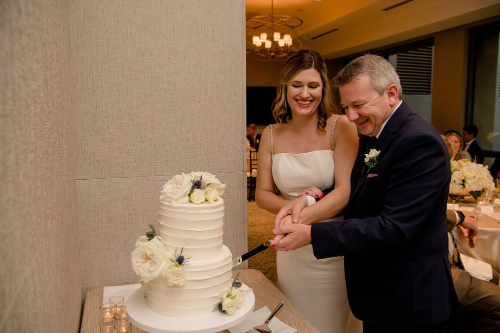 A traditional white wedding cake being cut during a reception celebration.
