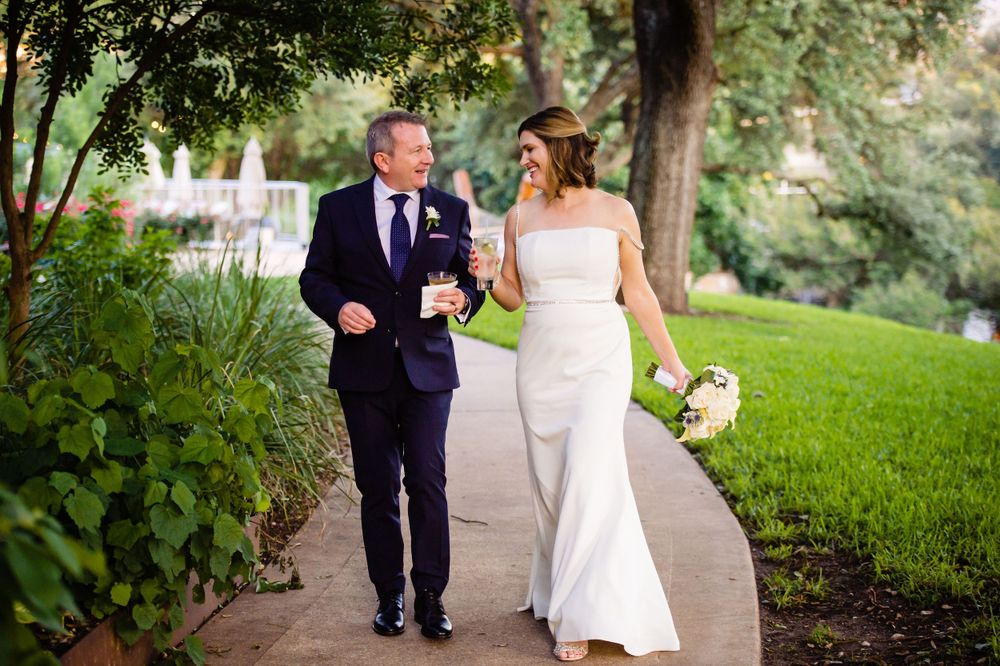 A couple walks together on a garden path surrounded by lush greenery.