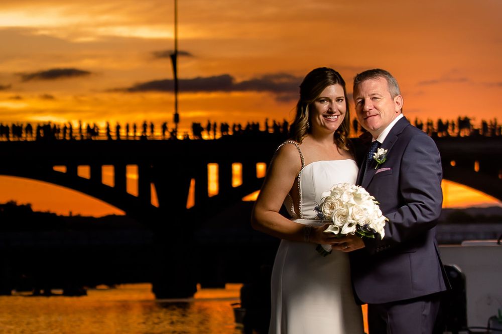 A romantic sunset portrait with a bridge silhouette in the background.