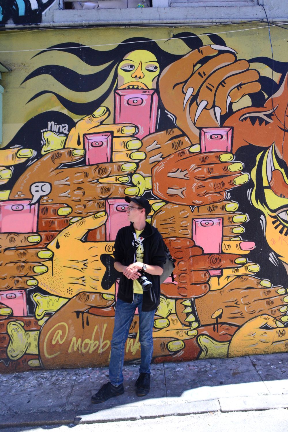Colorful graffiti mural featuring abstract faces and designs in orange and yellow tones on an urban wall.