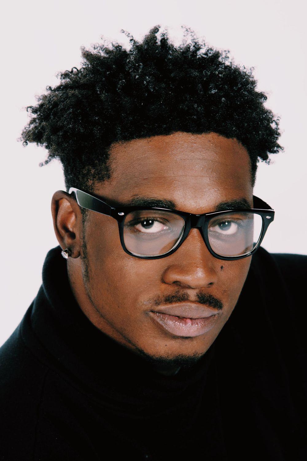 Studio portrait series featuring artistic black and white headshots with glasses against light background.