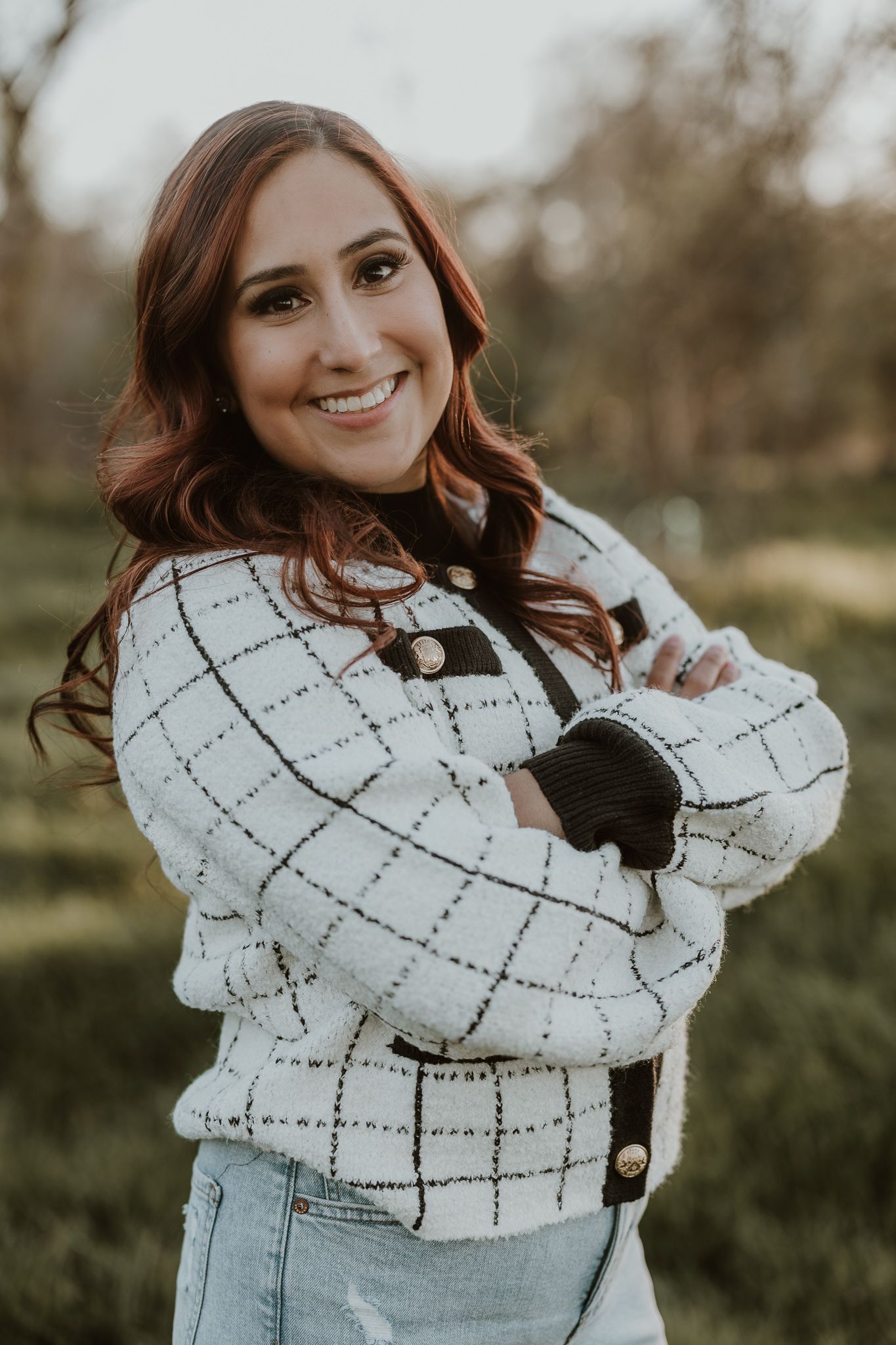 Portrait of person wearing white checkered sweater against natural outdoor background.