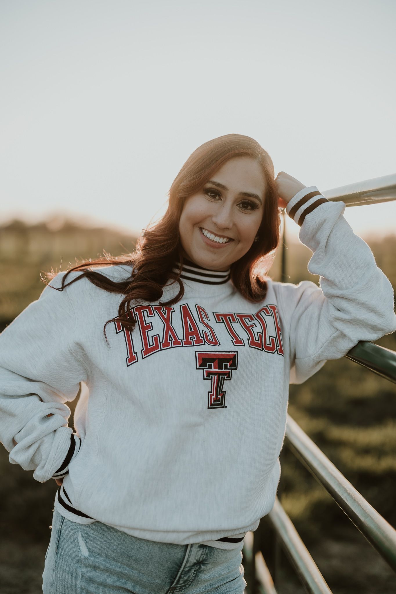 Casual portrait in Texas Tech university sweatshirt against sunset backdrop.