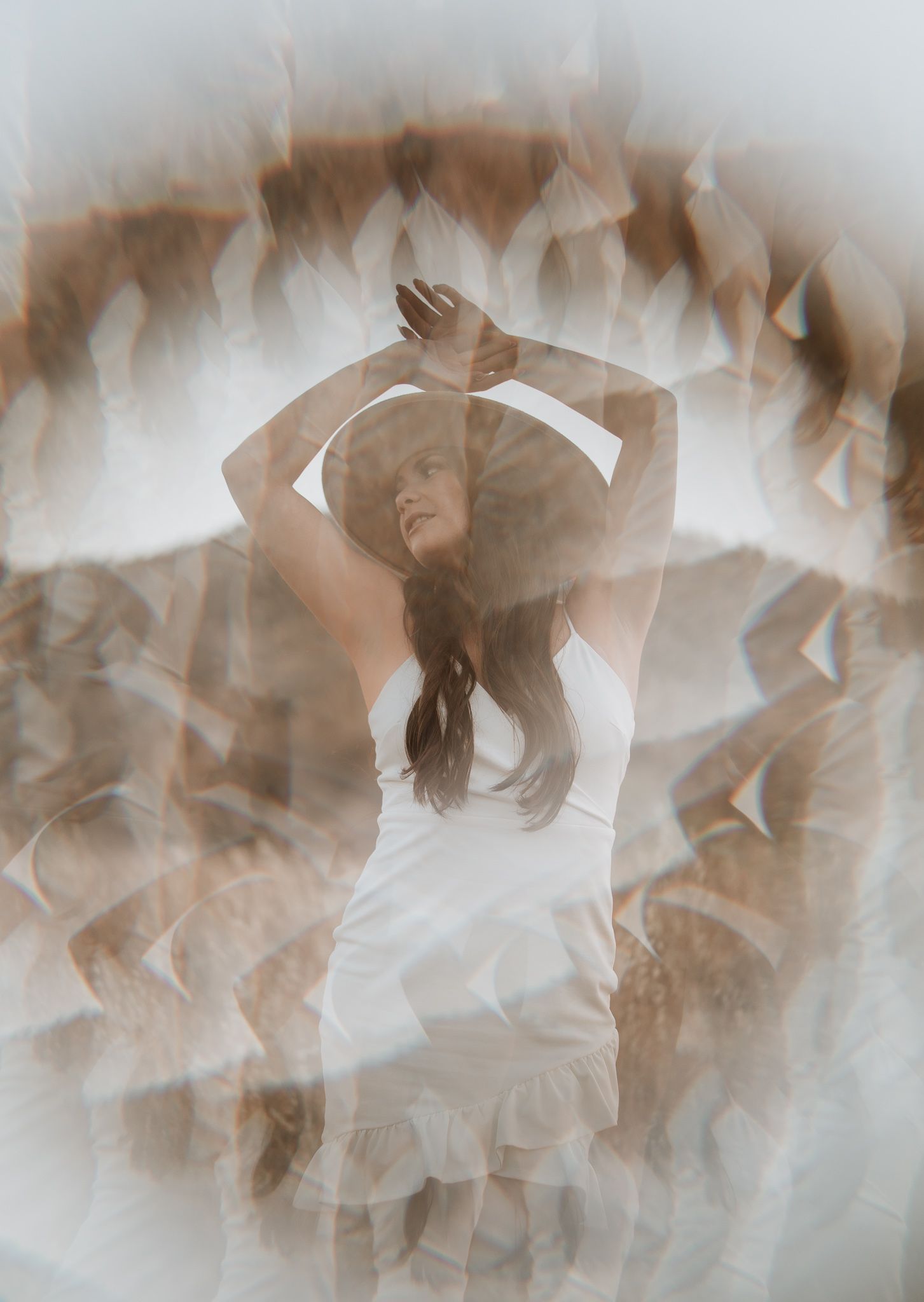 Artistic double exposure portrait showing a dancer in white dress with flowing movement against abstract background.