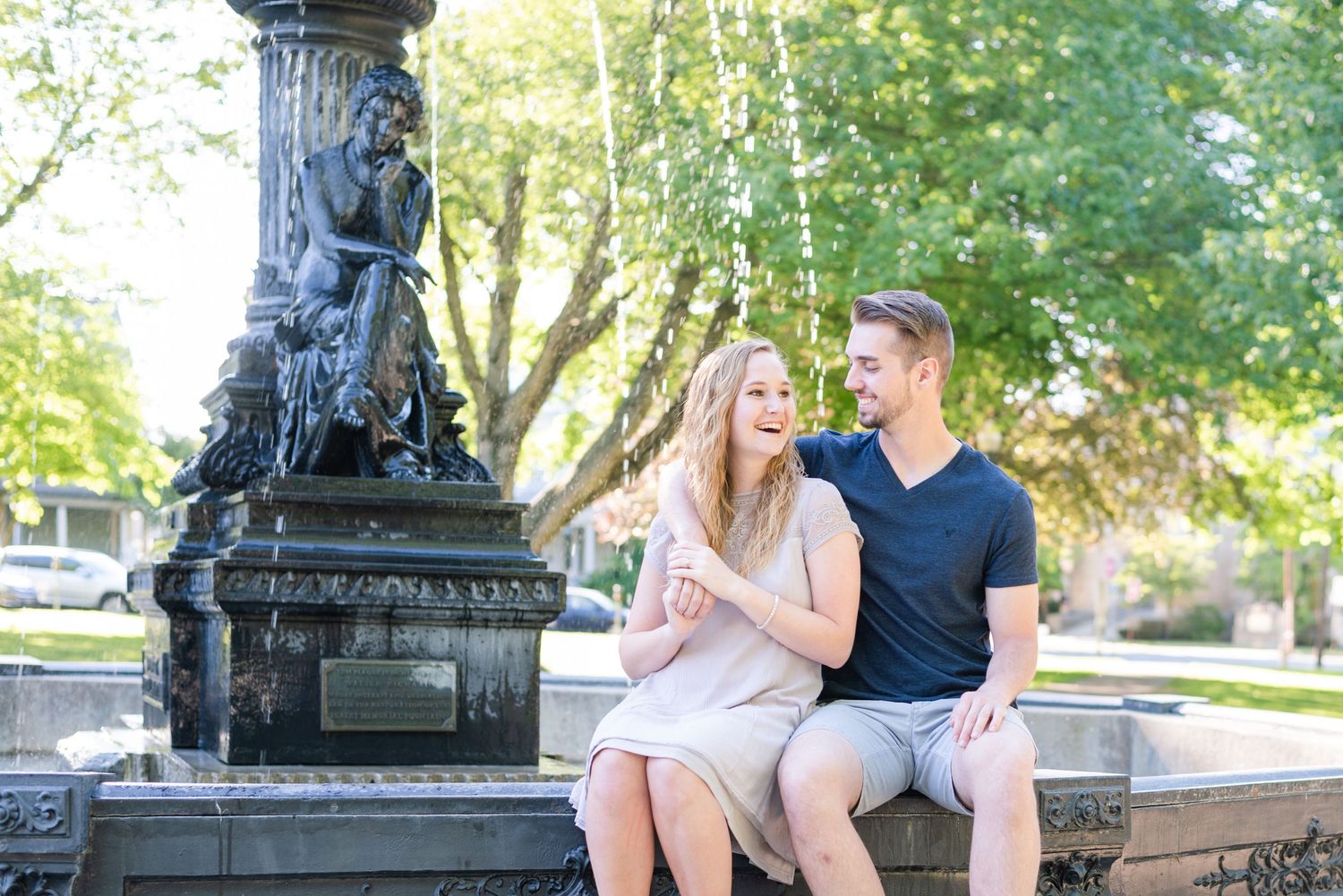Couple sitting in front of fountain laughing for engagement in Franklin Pennsylvania