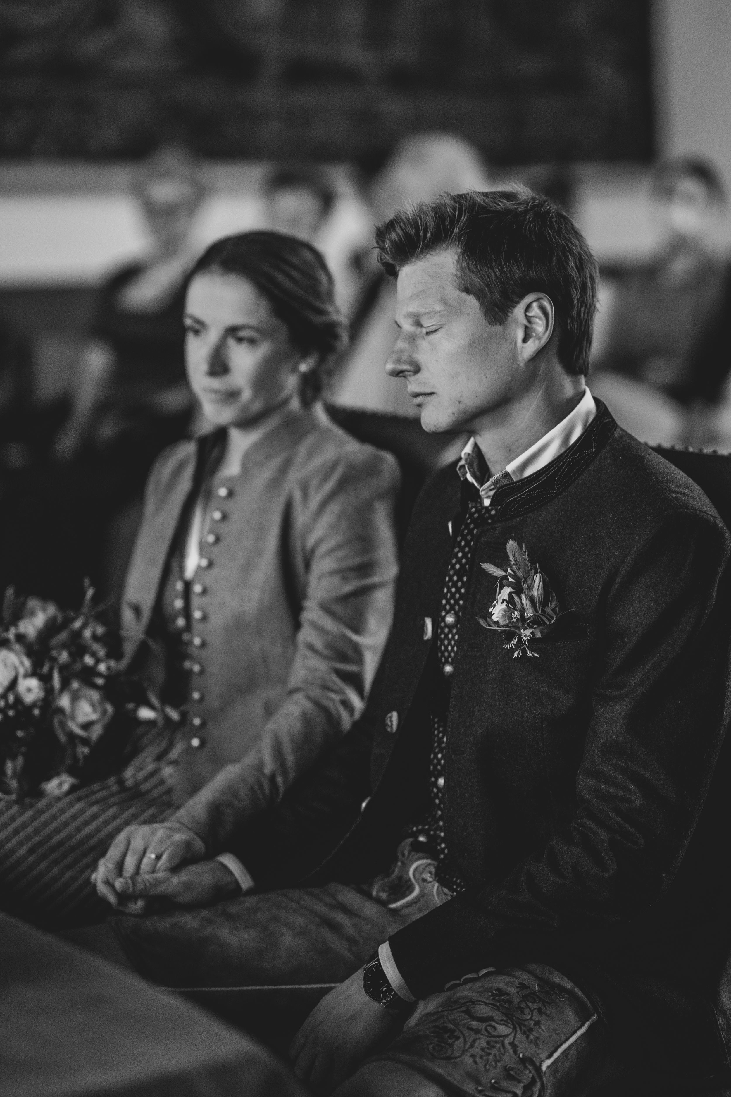 Vintage-style black and white photograph of couple seated during formal ceremony.