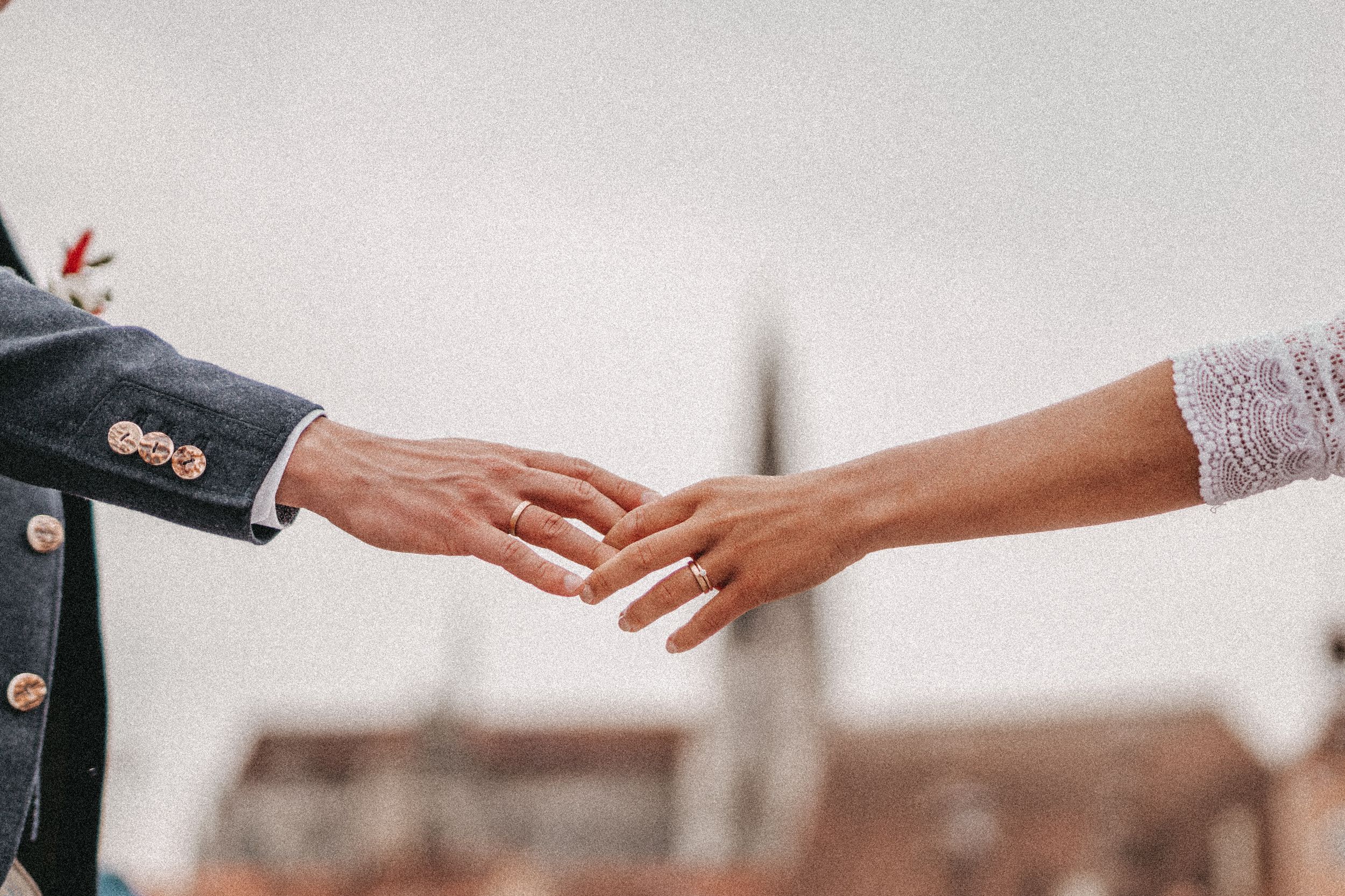 Close-up of hands reaching for each other against blurred European architecture.