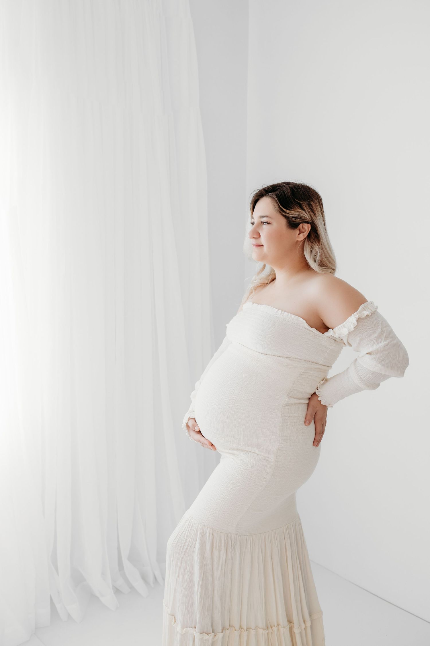 White minimalist boho room with pregnant woman posing for maternity pictures in Santa Fe, NM by baby photographer.